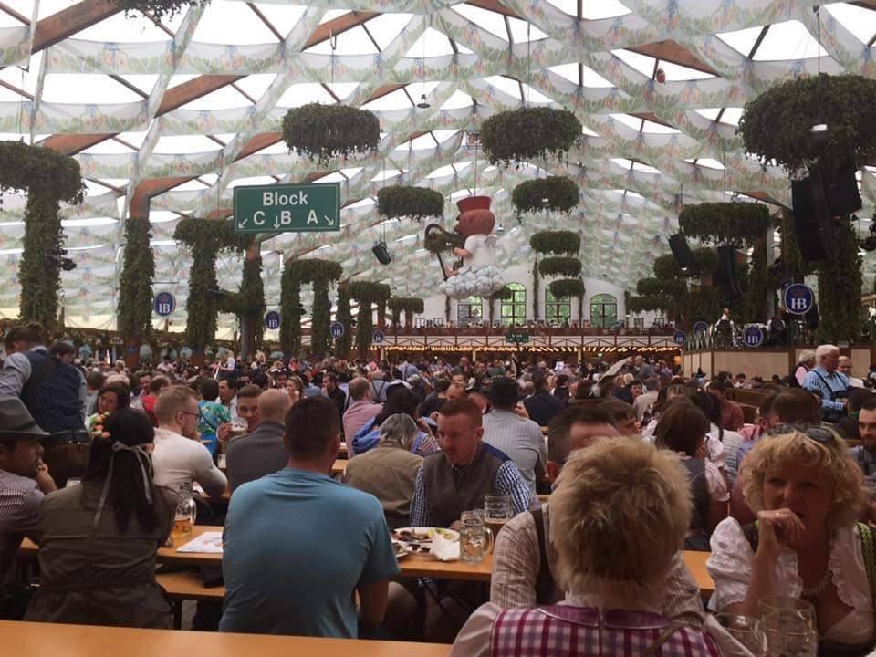 A large group of people sitting at tables in a tent

Description automatically generated