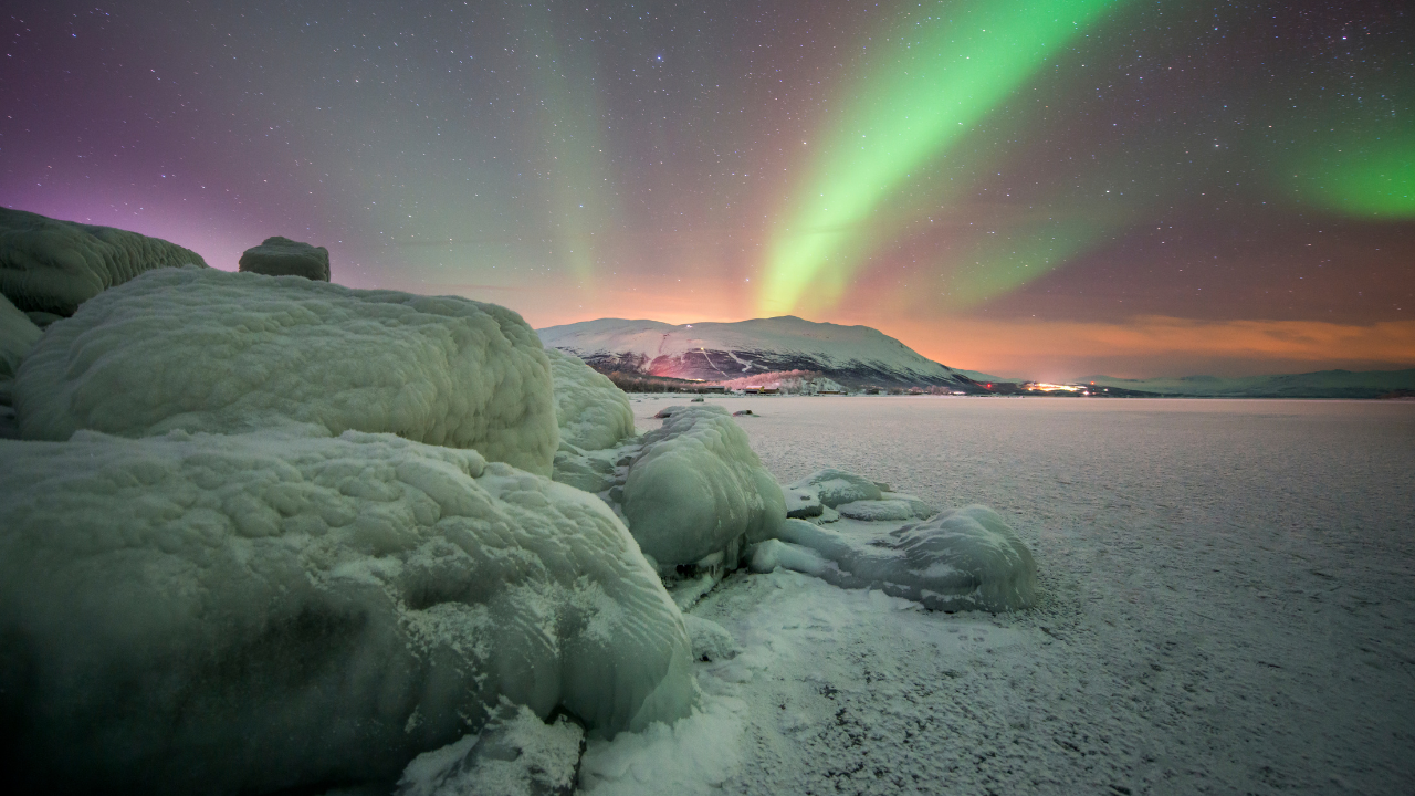 A snowy landscape with a green aurora borealis in the sky

Description automatically generated
